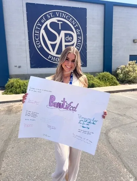Lindsey Wawrzyniak holding a Beautifeel poster after a presentation